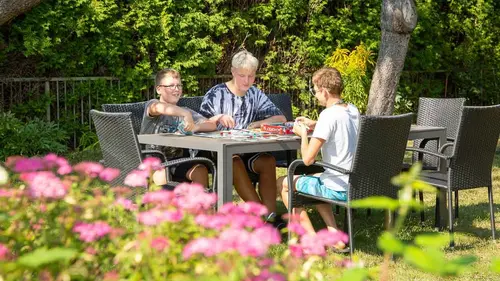 Drei Jugendliche sitzen in einem Garten an einem Tisch