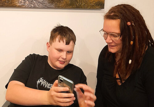 Ein Junge zeigt einer Fachkraft etwas auf dem Handy