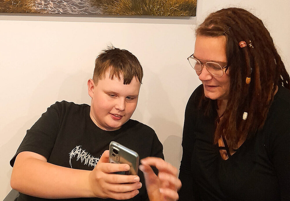 Ein Junge zeigt einer Fachkraft etwas auf dem Handy