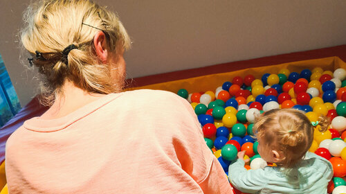 Eine Frau spielt mit ihrem Kind in einem Bällebad