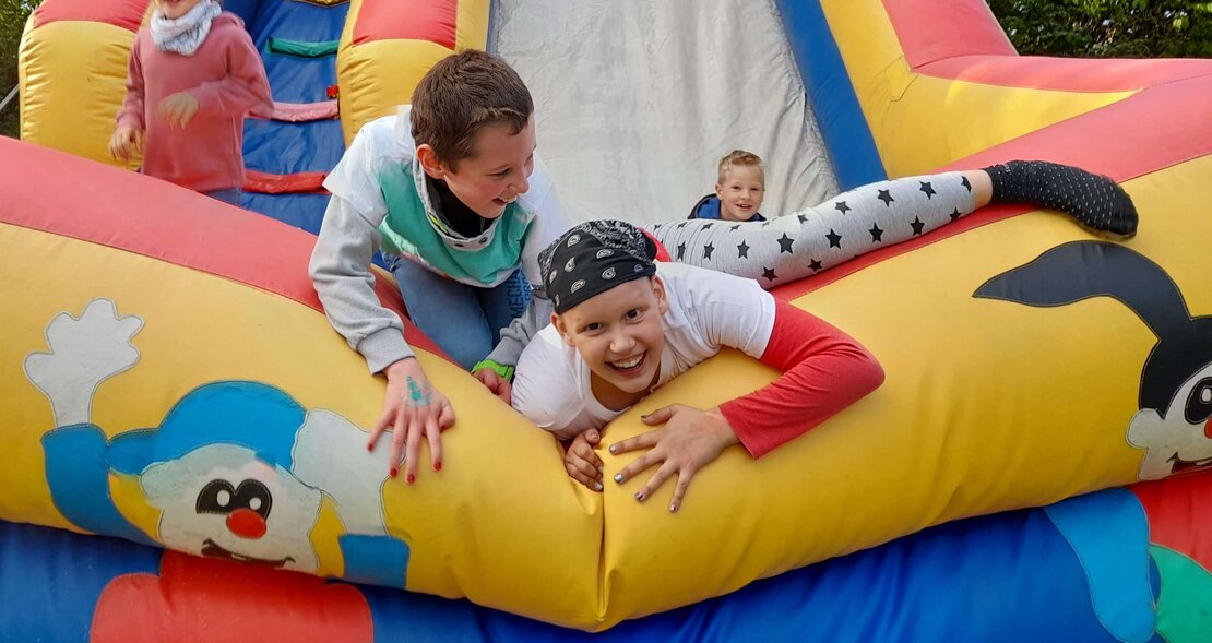 Drei Kinder spielen auf einer Hüpfburg.