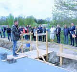 Viele Personen stehen auf einr Baustelle, eine Person hält eine Rede