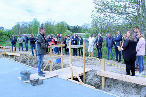 Viele Personen stehen auf einr Baustelle, eine Person hält eine Rede